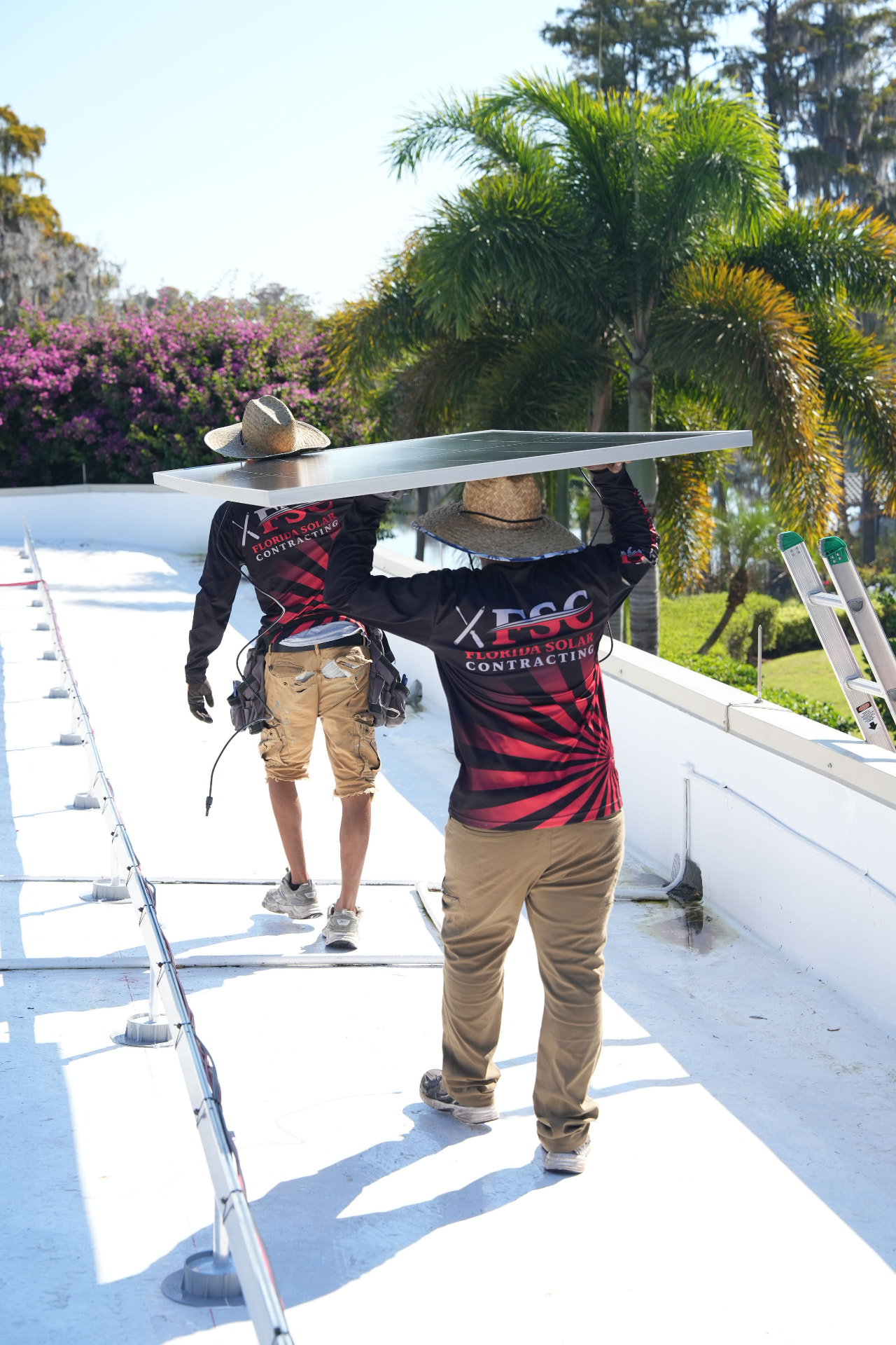 FSC technicians carrying a solar panel across a roof